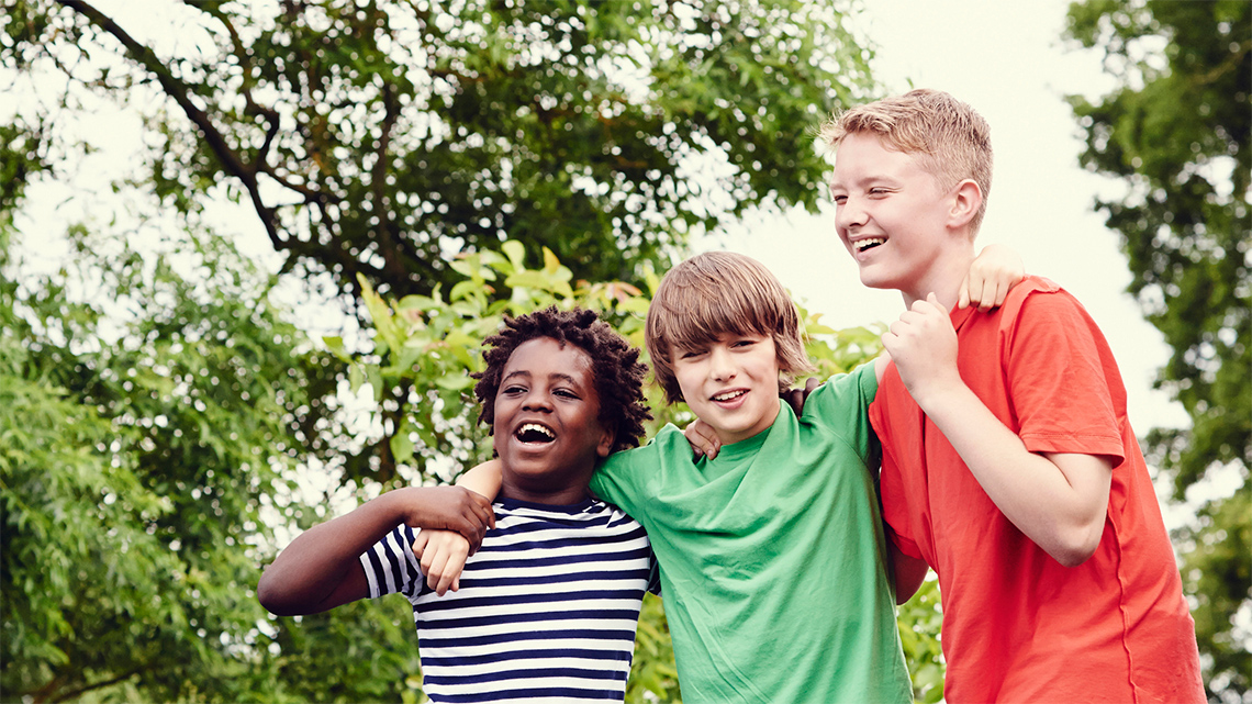 Three kids with their arms around each other smiling and having fun.
