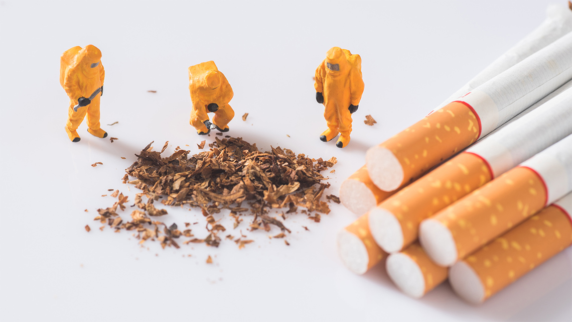 People in protective hazmat suits examine the ingredients of a cigarette.