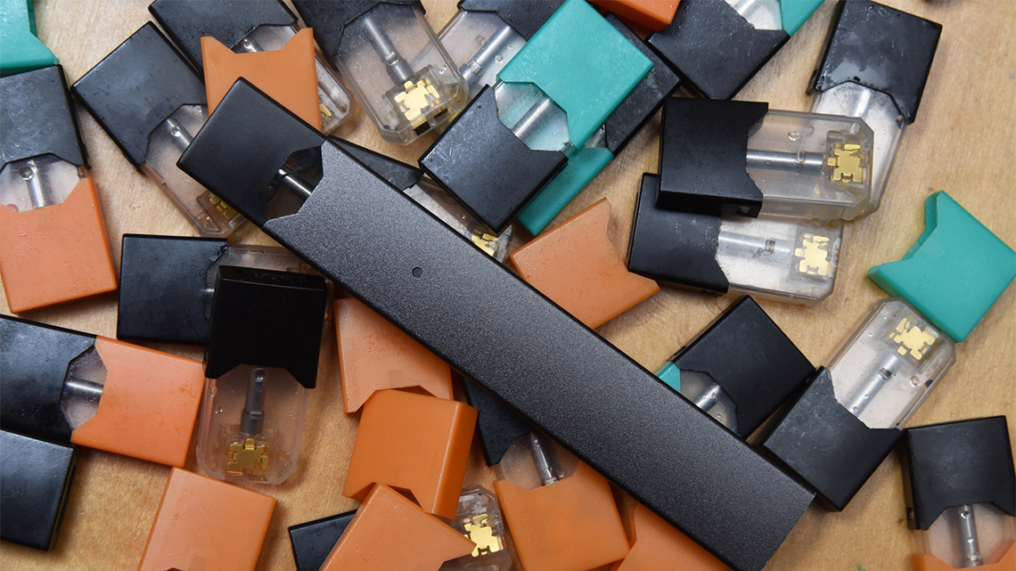 A vape pen on top of a pile of vape pods or cartridges.