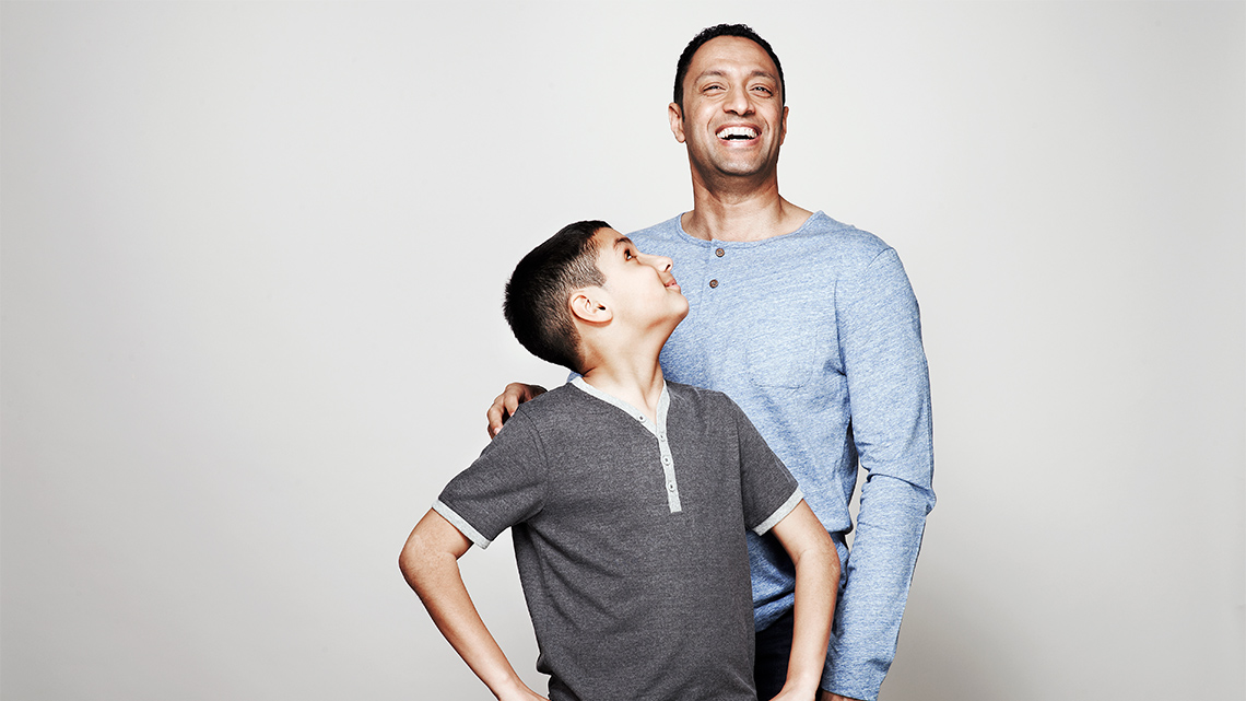 A child and an adult smiling. The child is looking up at the adult.