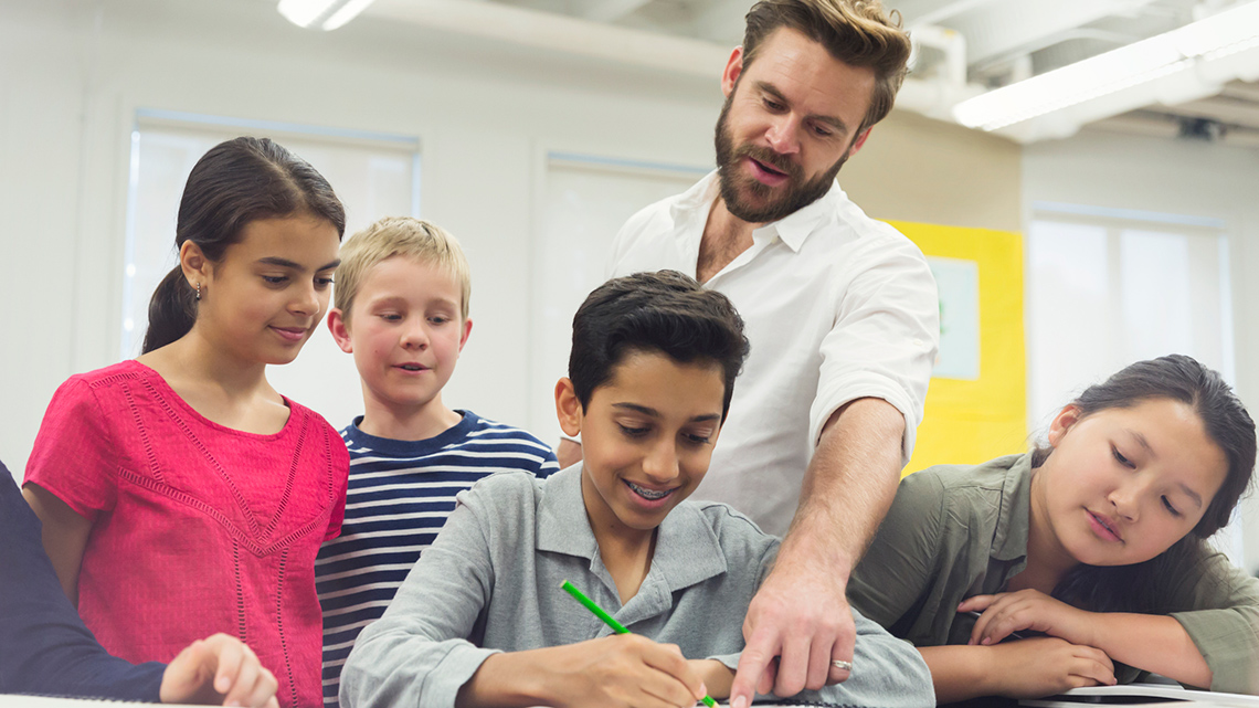 A teacher teaches a group of classmates.
