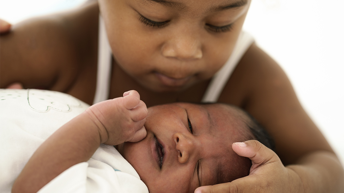 A child is holding a baby gently.