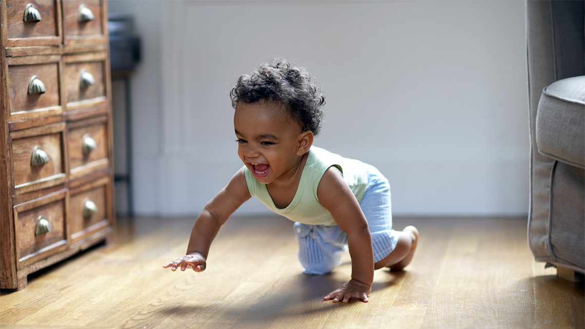 A child is crawling with one hand off the ground.