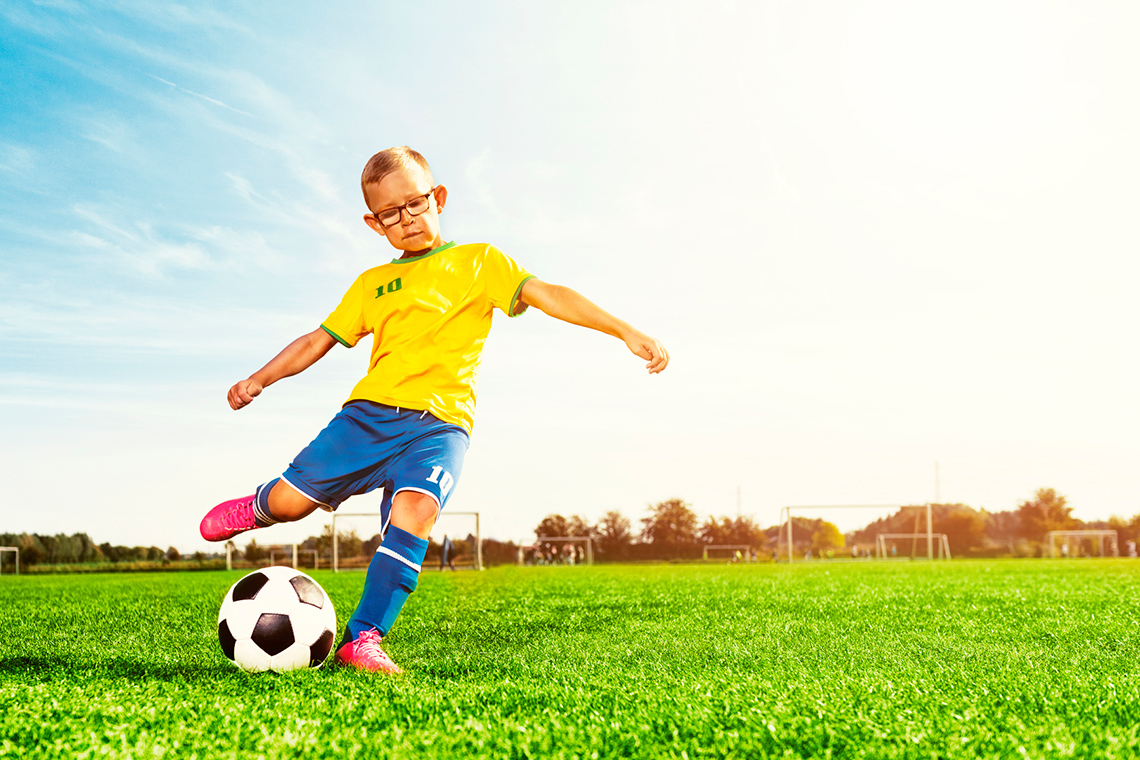 A child is kicking the ball using their feet.