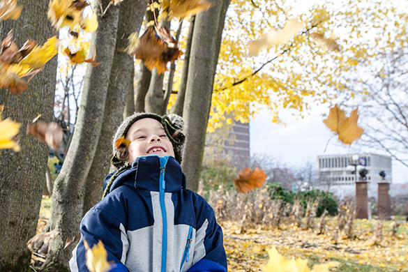 A child is looking at the leaves that are falling.