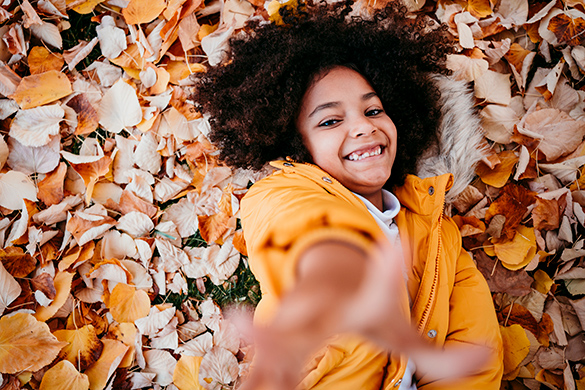 A child is catching the falling leaves.