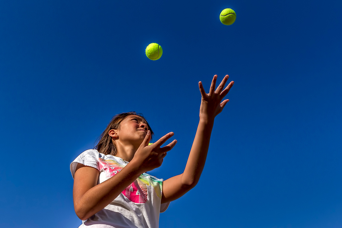 A child is throwing a ball from one hand to another.