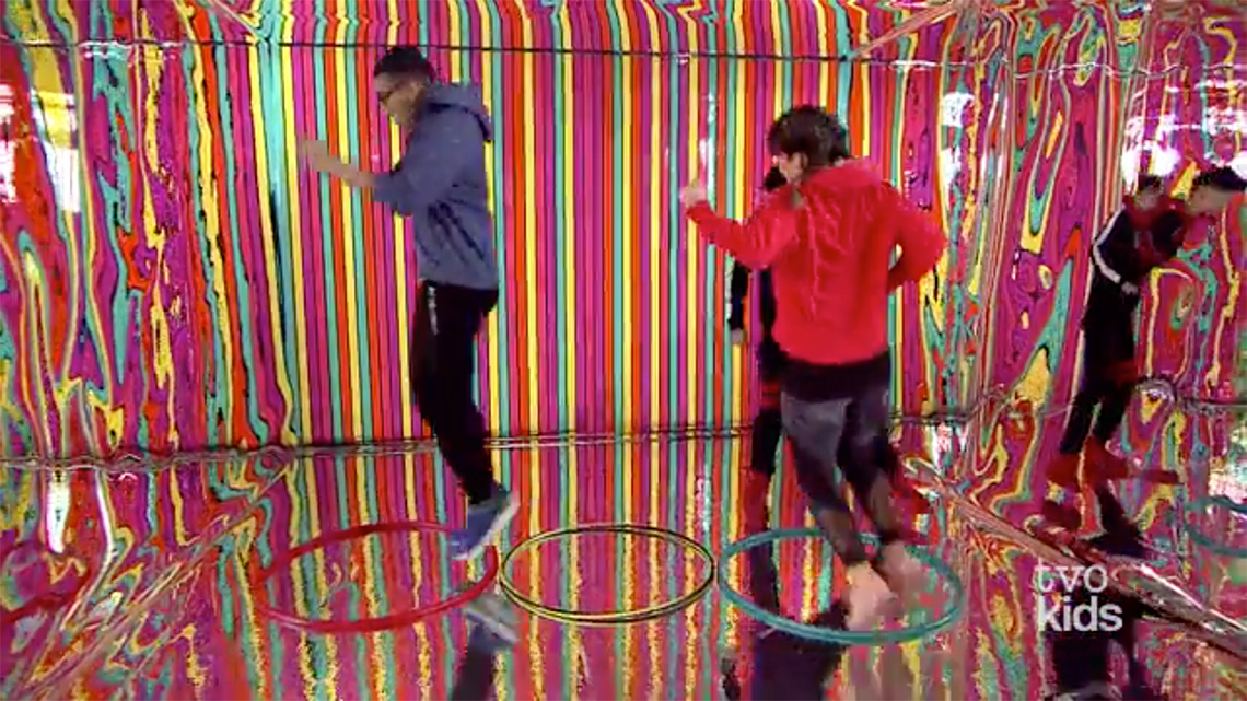 Two people are jumping in hula-hoops on the floor.