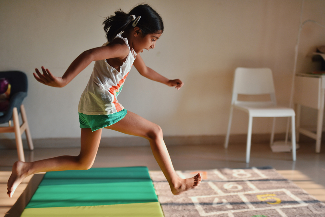A child is jumping forward on stepping mats.