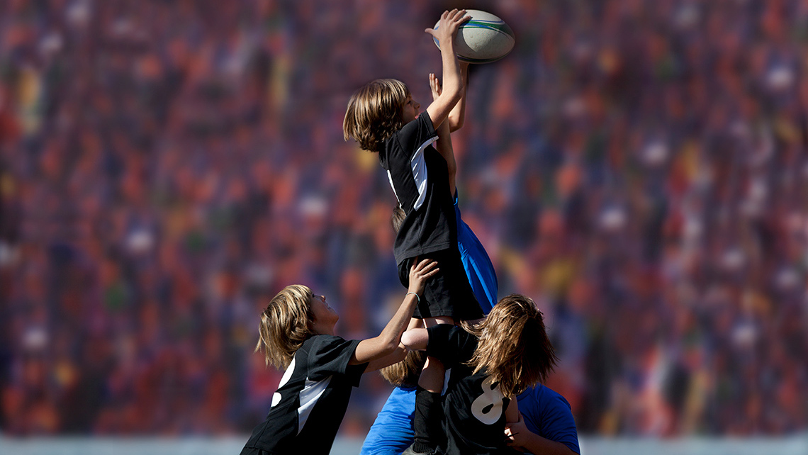 Rugby players, from two different teams, are trying to receive the ball.