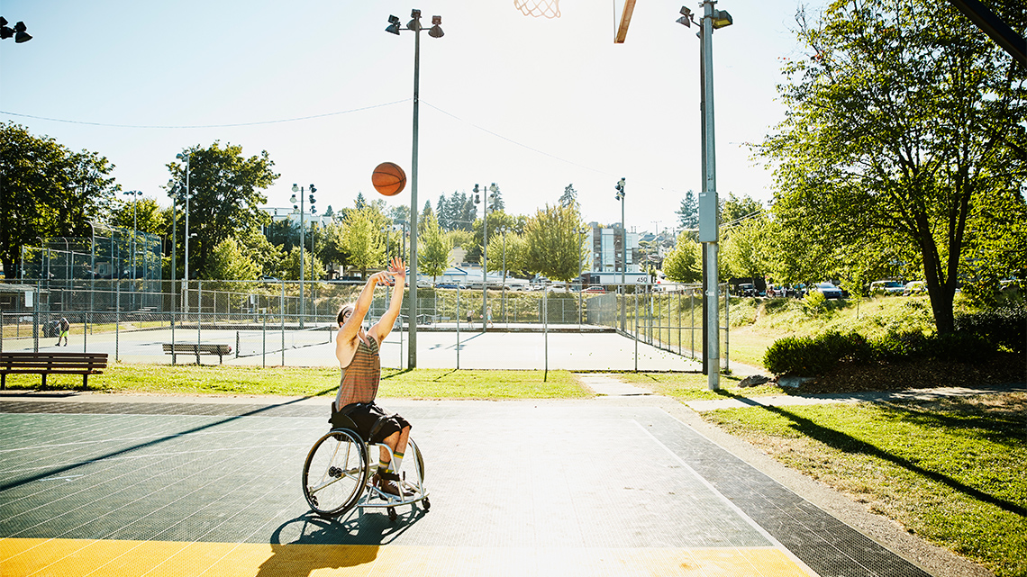 A person in a wheelchair shooting a basketball into a hoop.
