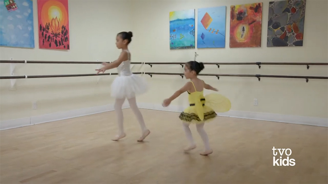 Two girls moving their arms up and down, like a flying motion.