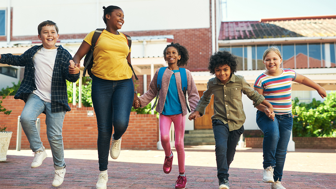 A group of children holding hands and skipping.