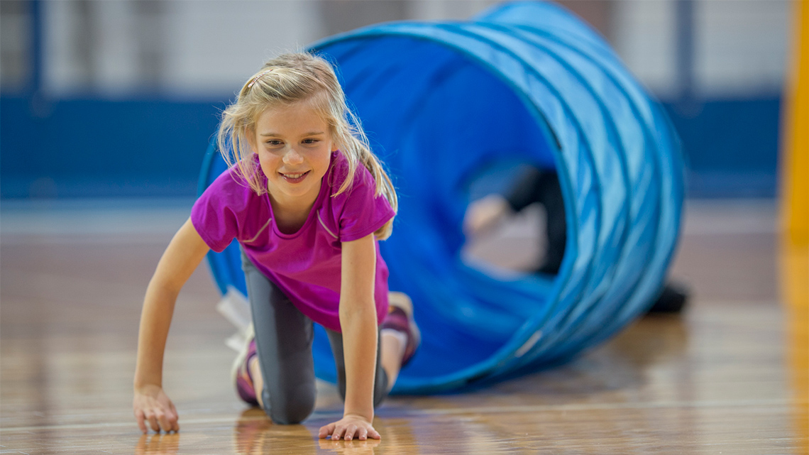 A child crawling through a tube on their hands and knees. 
