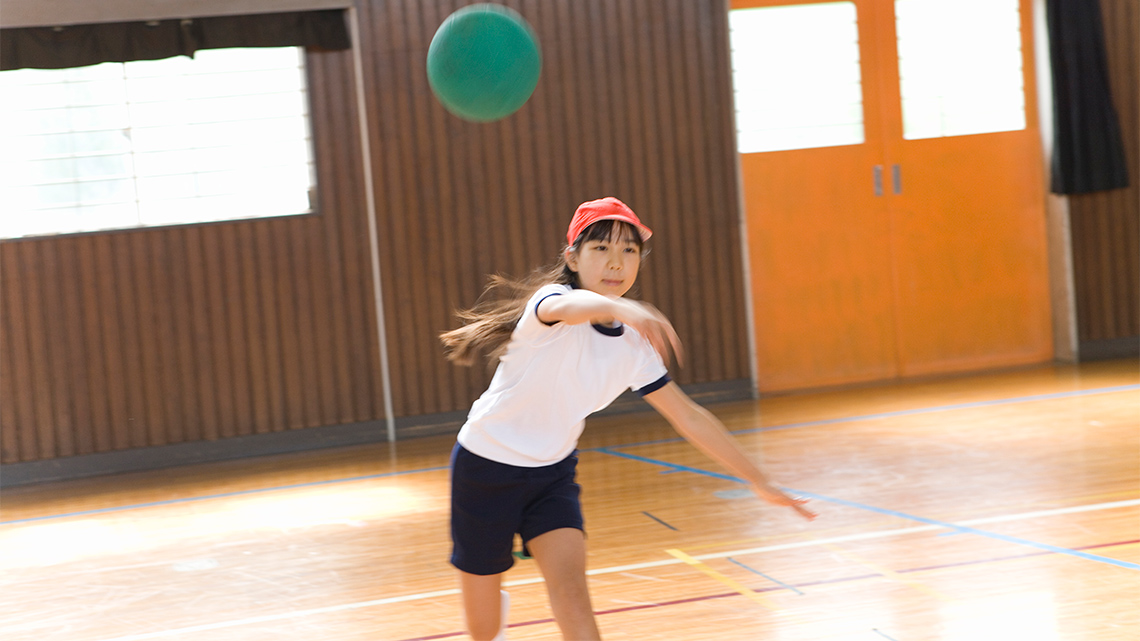 A girl throws a dodgeball.