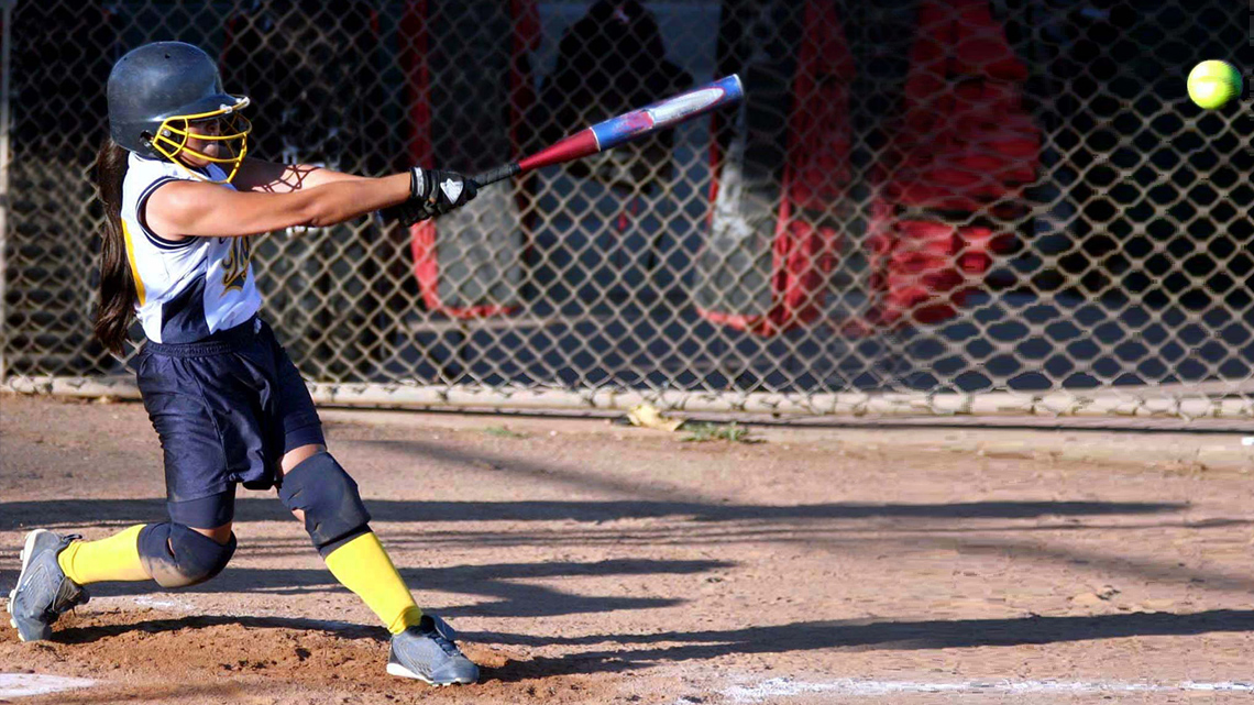 A person swings a baseball bat and hits a baseball.