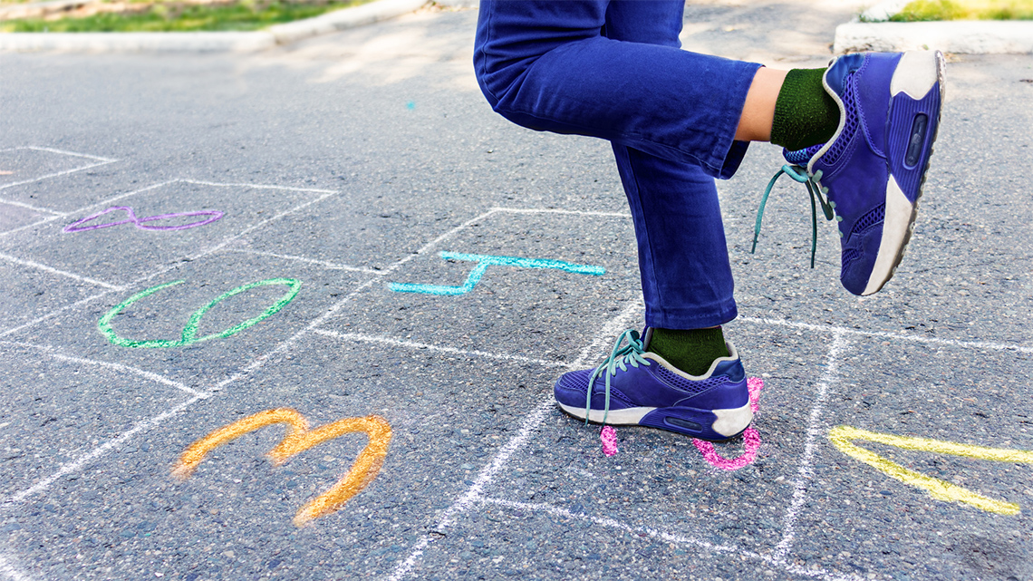 A child hopping on one foot through a hopscotch course.