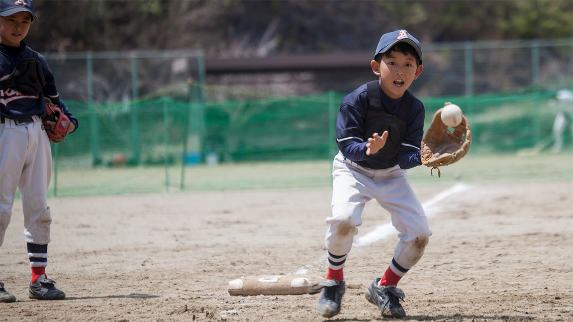 A child plays baseball and prepares to catch the ball in his baseball glove.