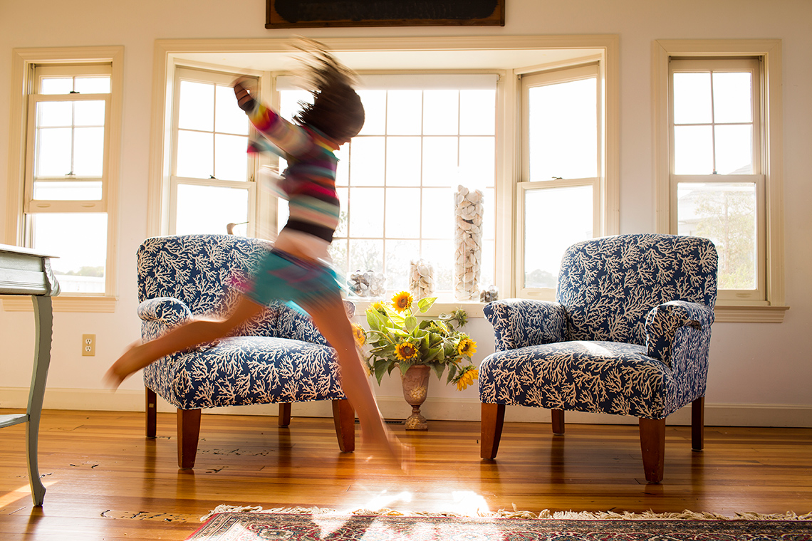 A child leaping from one foot to the other in a living room.