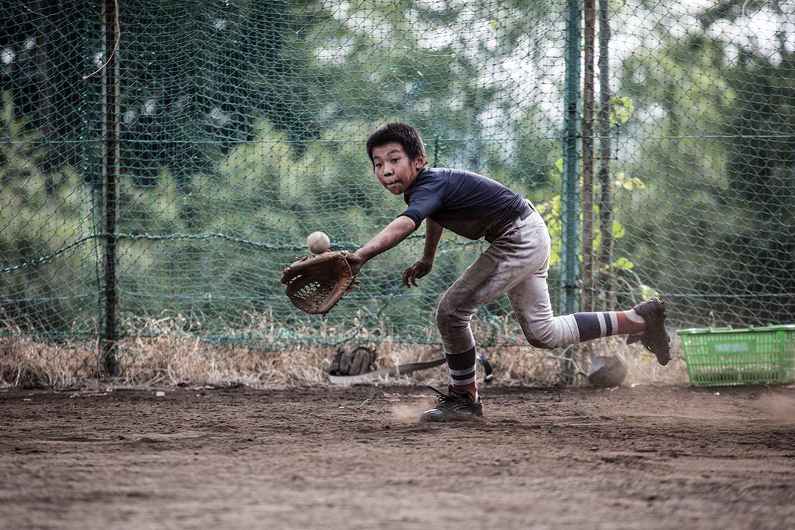 A child running to receive a baseball with their glove.
