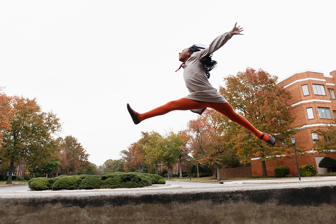 A person is jumping outside with their arms outstretched.