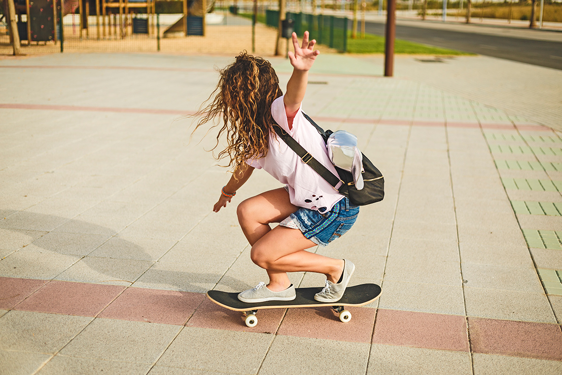 A person is balanced on a skateboard with their arms stretched out on each side.