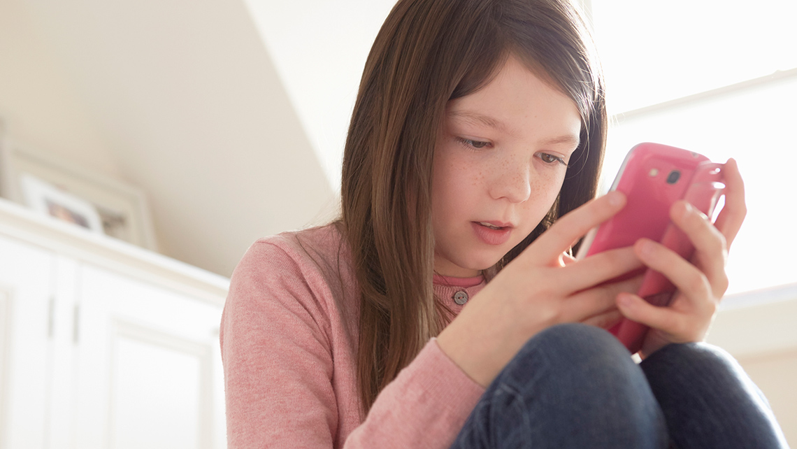 A person smiles while looking at a mobile device.