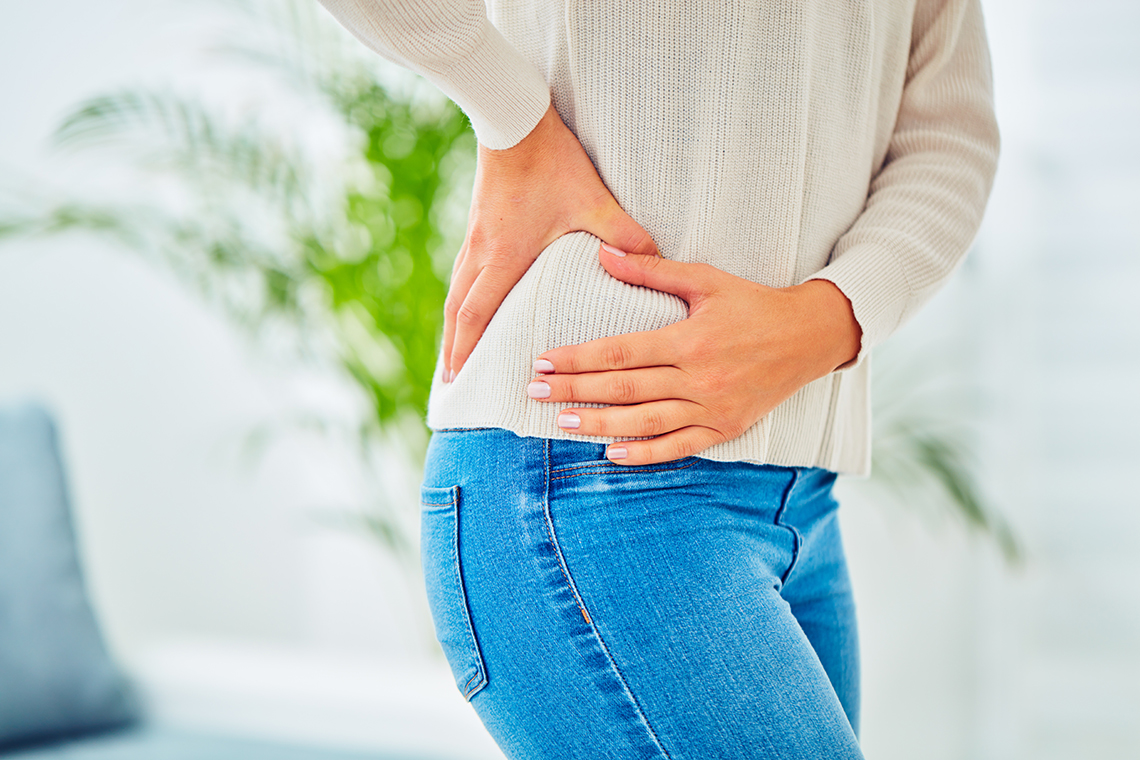 A person’s hands are cupped around their hip.