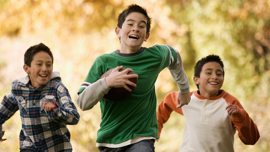 A person is running while carrying a football in their right hand.