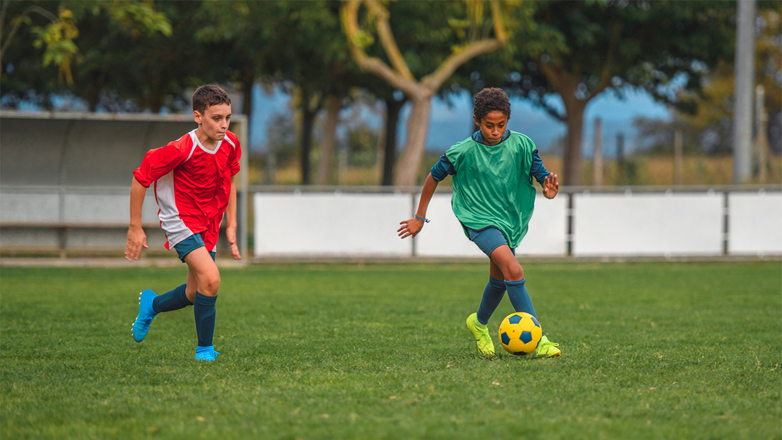 One person is dribbling the soccer ball while another person tries to take the ball away. The person with the ball keeps it close to their feet.