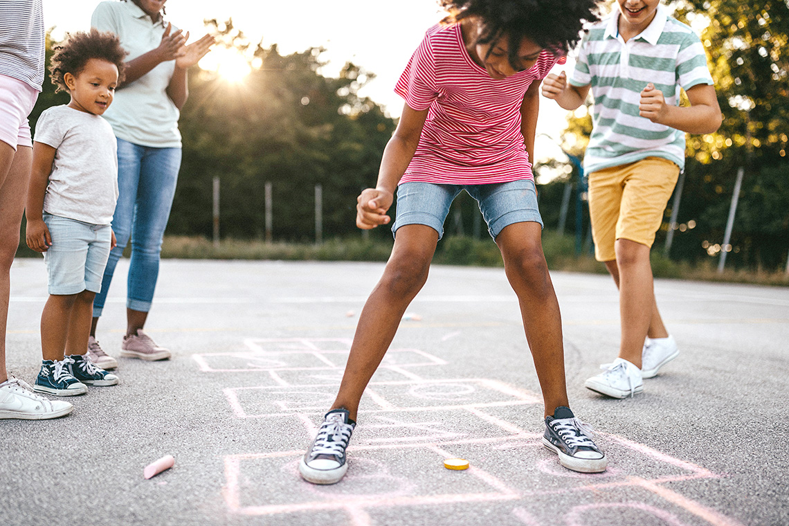A person looks down at a chalk-drawn hopscotch course and gets ready to play hopscotch.