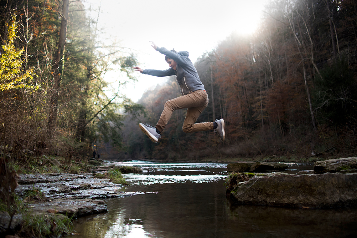 A person jumps across a river.