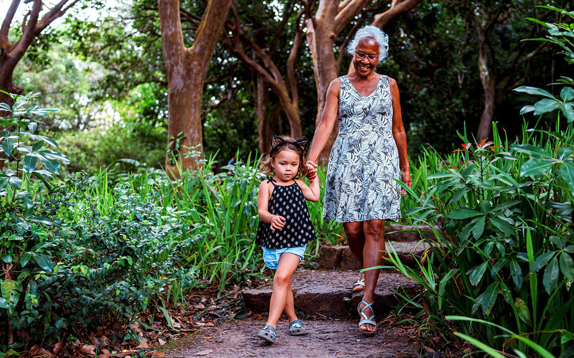 A child and their guardian walking through a forest path.