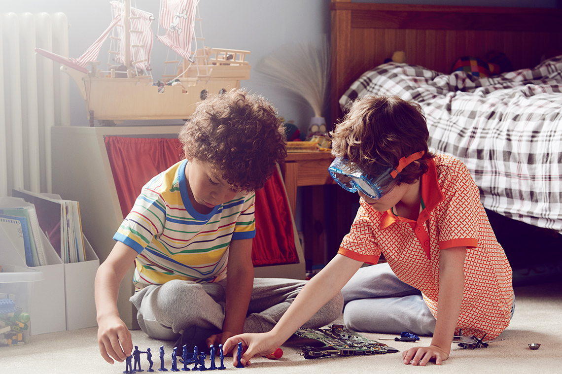 Two children playing together on the floor and sharing little figurines.