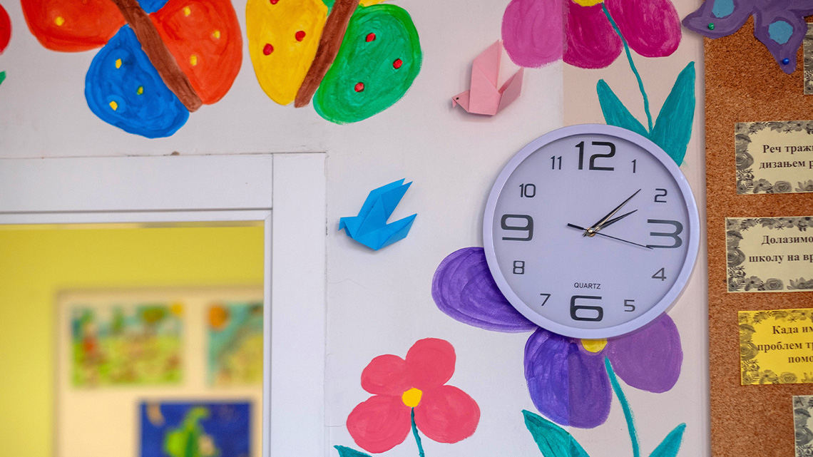 A clock hanging on a classroom wall.