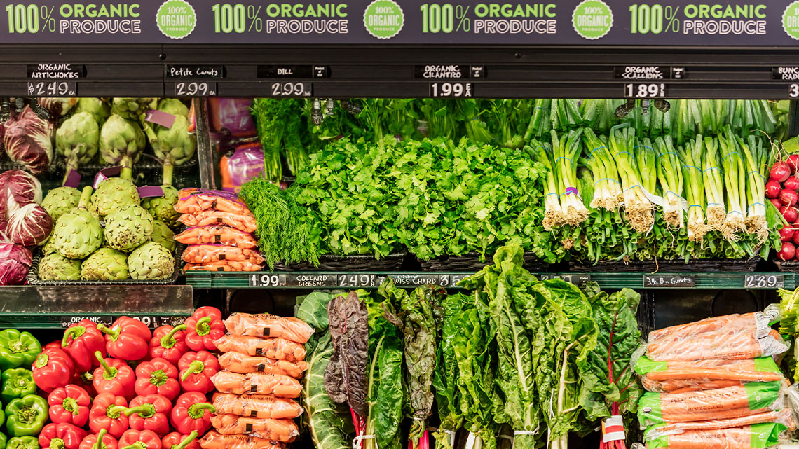 Vegetables are neatly arranged in a grocery store display with visible price tags highlighting fresh produce options.