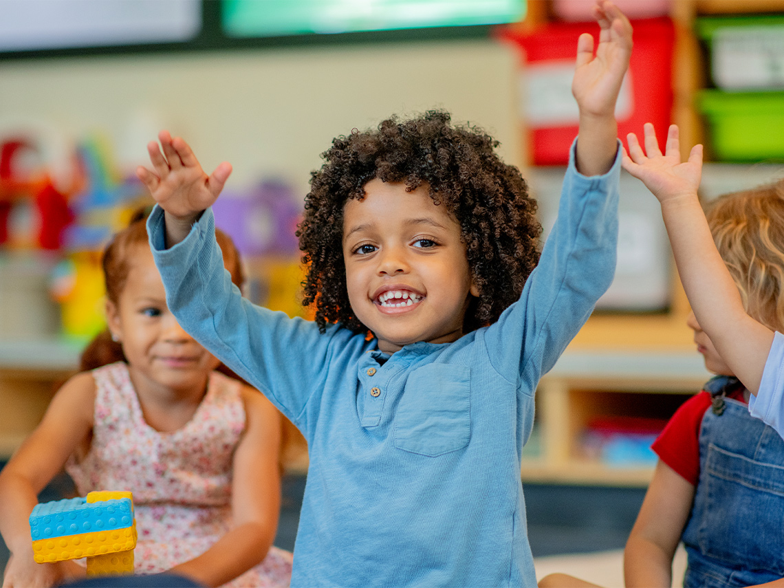 A young child holding their arms up.