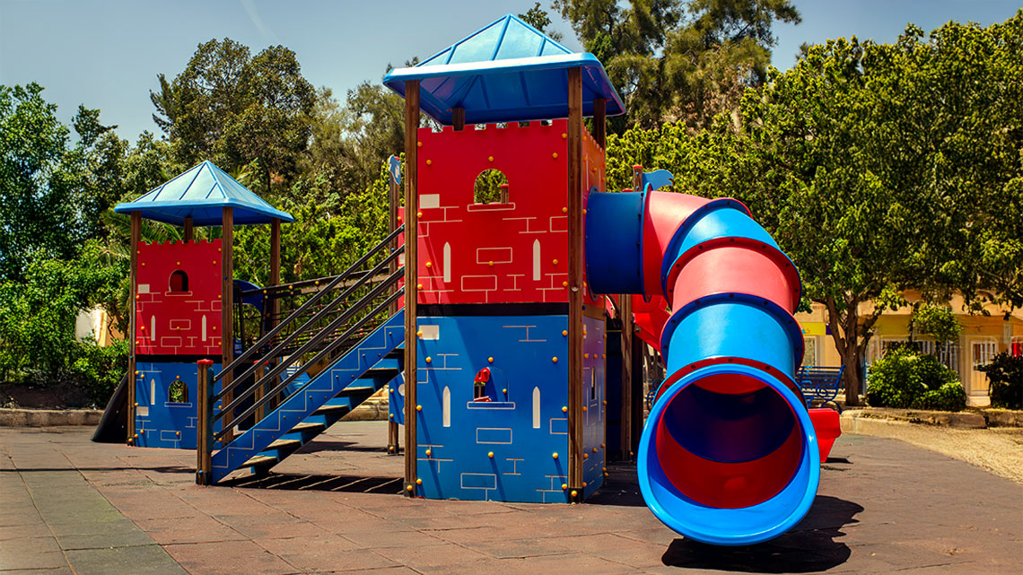 A large outdoor playground structure with towers, stairs, and a curved slide is shown.