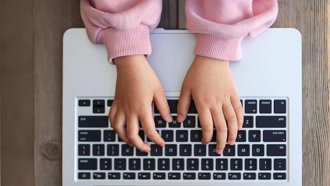 Hands typing on a laptop keyboard.