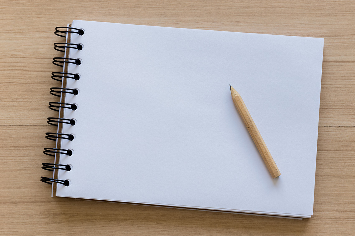 A pencil resting on top of a notebook.
