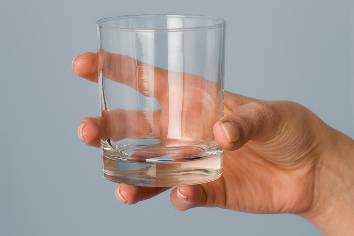 A hand holding an empty glass.