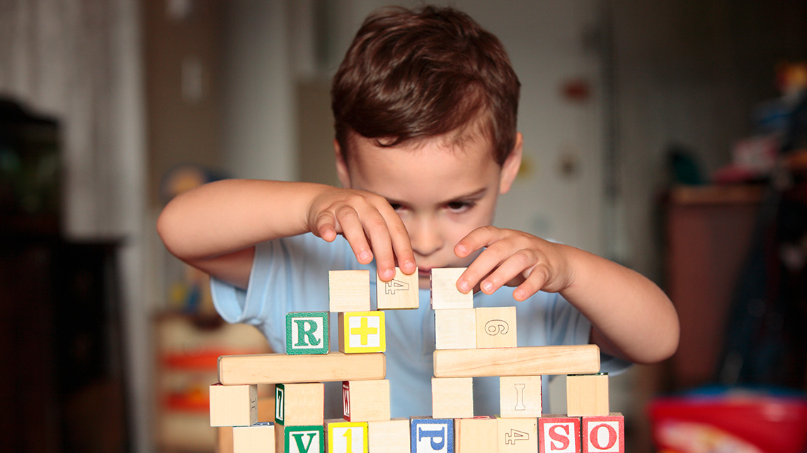 A child stacks wooden blocks to make a tower.