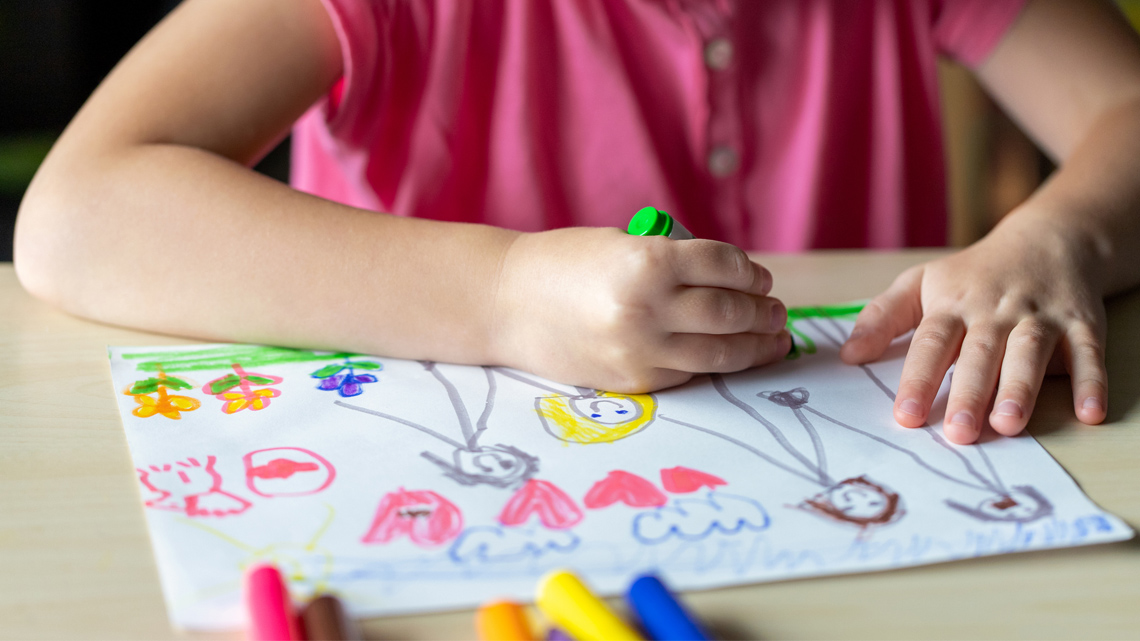 A young child is drawing a picture with a marker.