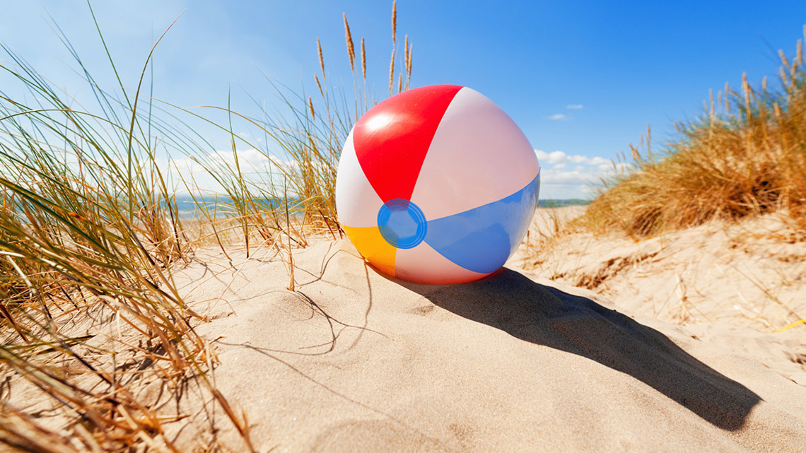 A beach ball resting in the sand.