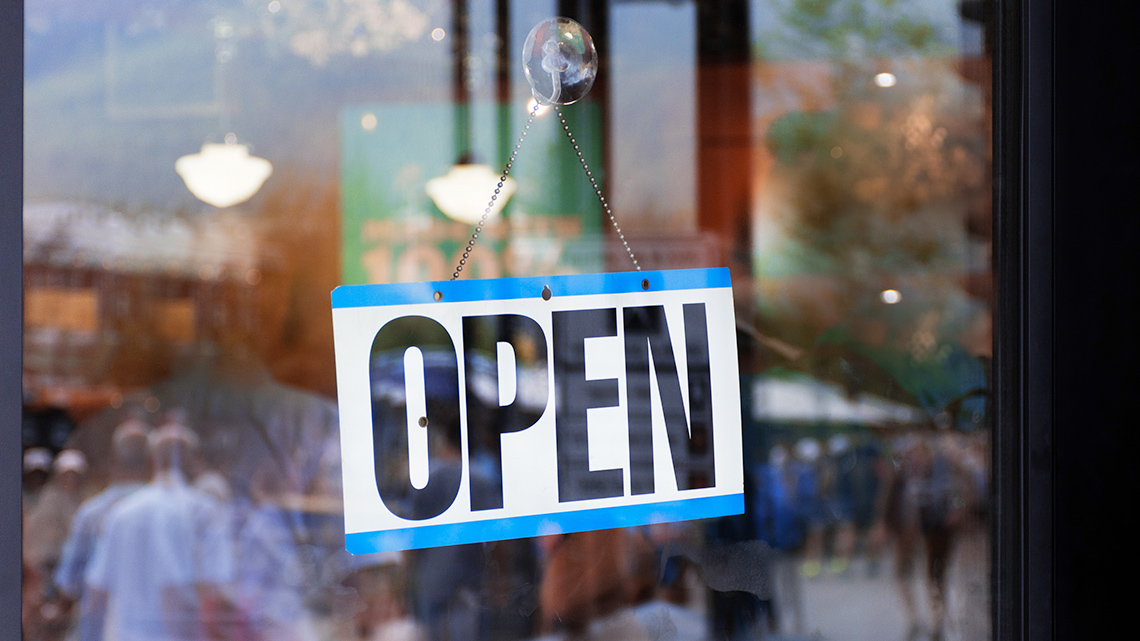 A sign on a store window with the text, open.