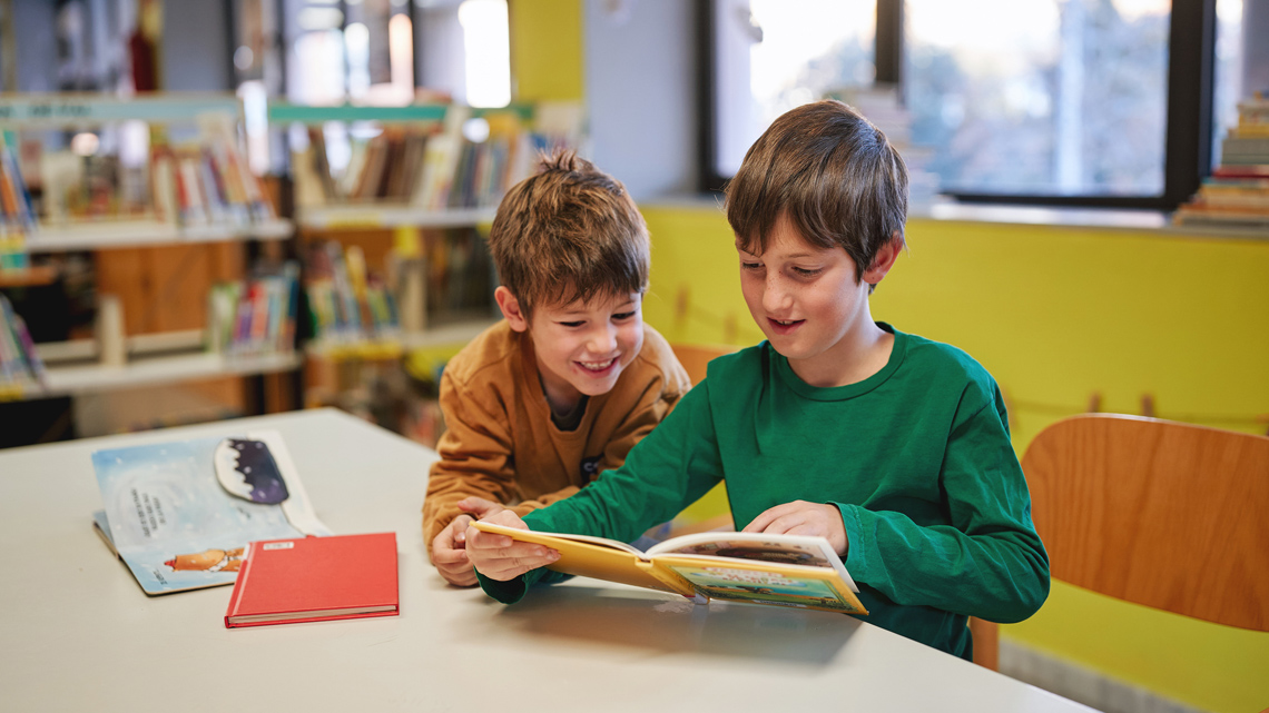 Two learners reading a book.