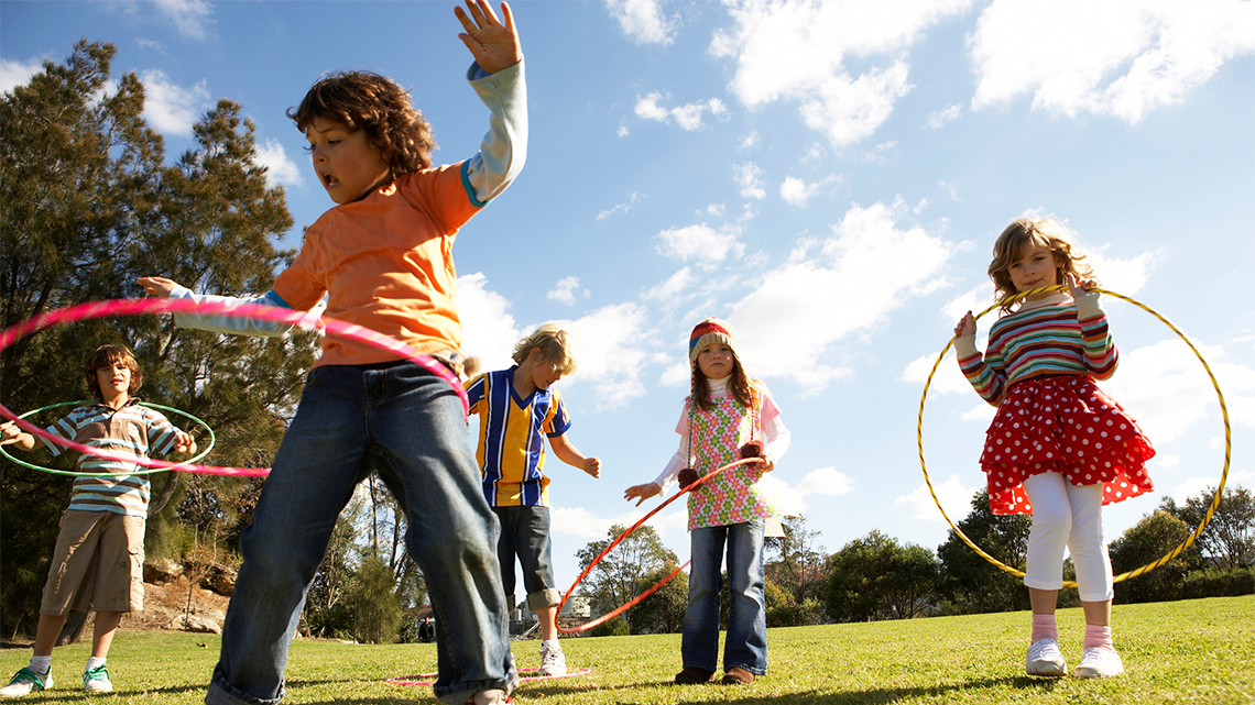 A group of kids are playing outside with hula hoops.
