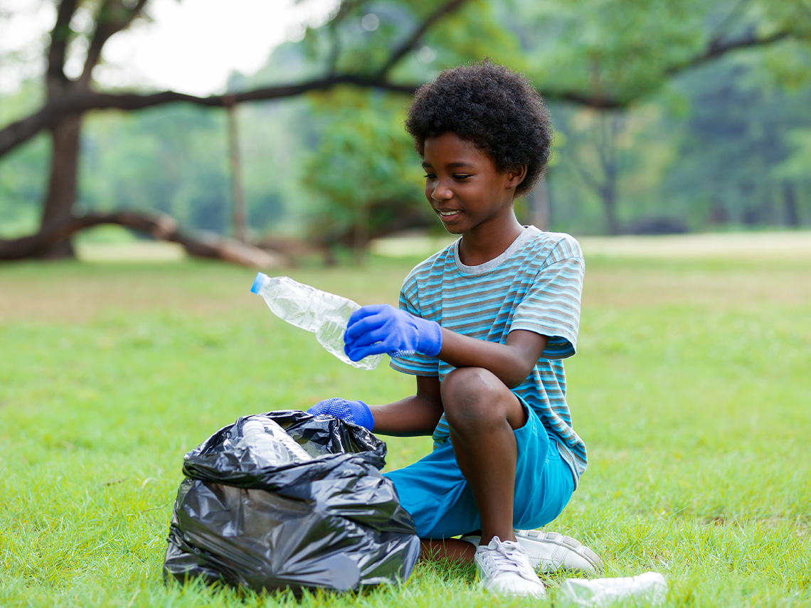 A learner picking up garbage in a park.