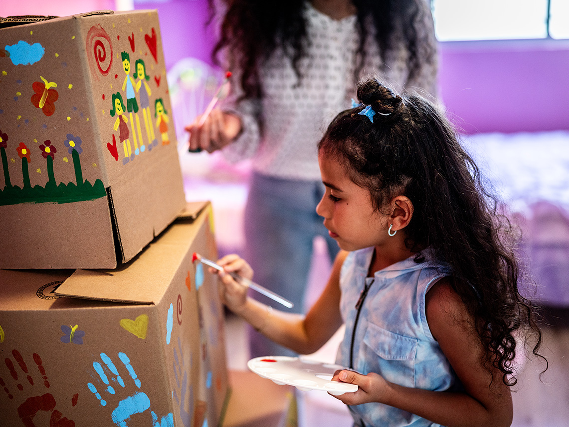 A learner painting on a cardboard box.