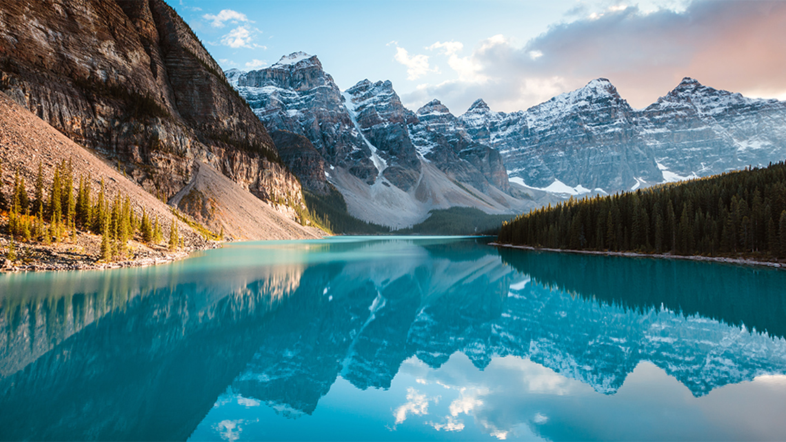 A lake surrounded by mountains with trees along the shore.